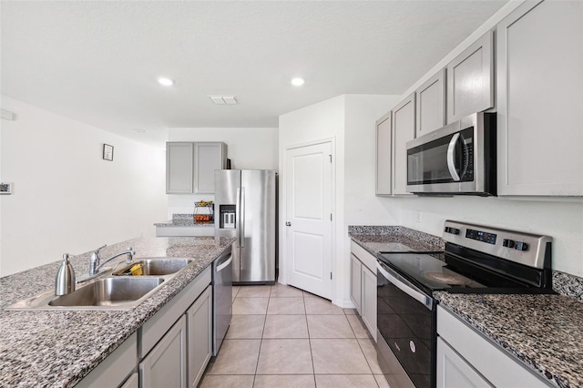 33657 Field Maple Loop, Wesley Chapel, FL 33545 - kitchen featuring appliances with stainless steel finishes, gray cabinets, light tile patterned flooring, dark stone counters, and recessed lighting
