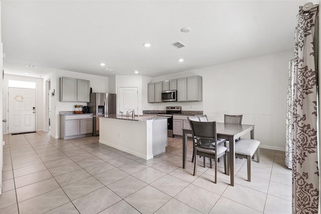 33657 Field Maple Loop, Wesley Chapel, FL 33545 - kitchen with gray cabinets, appliances with stainless steel finishes, an island with sink, stone counters, and recessed lighting