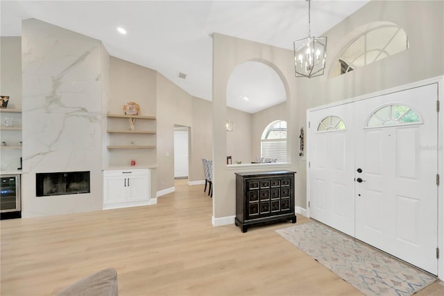 4617 Basswood St, Land O Lakes, FL 34639 - foyer featuring high vaulted ceiling, arched walkways, light wood-style flooring, a chandelier, and beverage cooler