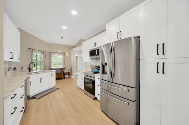 4617 Basswood St, Land O Lakes, FL 34639 - kitchen with appliances with stainless steel finishes, light wood-type flooring, white cabinetry, vaulted ceiling, and recessed lighting