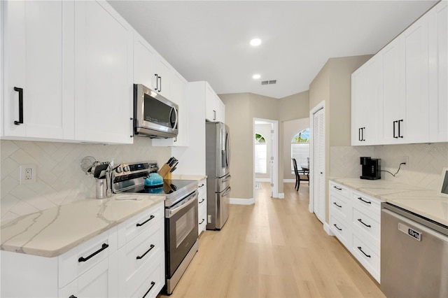 4617 Basswood St, Land O Lakes, FL 34639 - kitchen with appliances with stainless steel finishes, light wood-style flooring, decorative backsplash, white cabinets, and recessed lighting