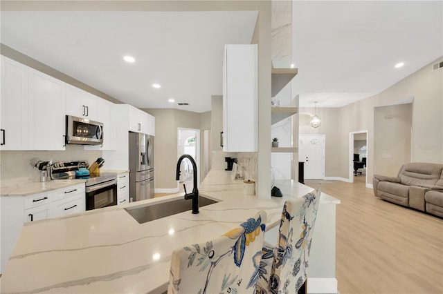 4617 Basswood St, Land O Lakes, FL 34639 - kitchen featuring appliances with stainless steel finishes, decorative backsplash, light stone countertops, light wood finished floors, and a peninsula