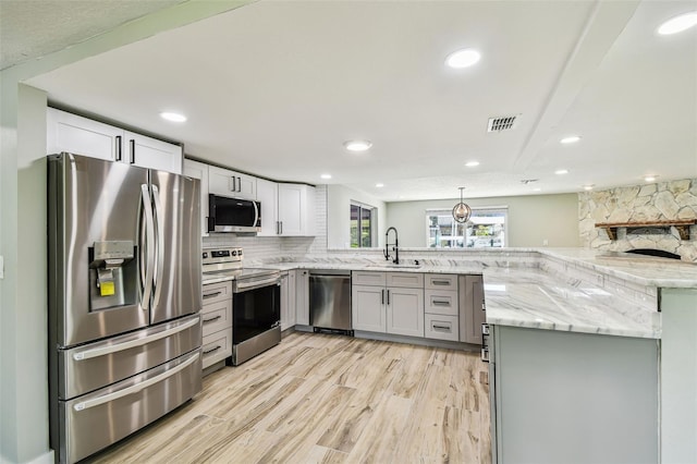 13909 Berkowitz Ave, Hudson, FL 34667 - kitchen featuring appliances with stainless steel finishes, a peninsula, tasteful backsplash, light wood finished floors, and light stone countertops