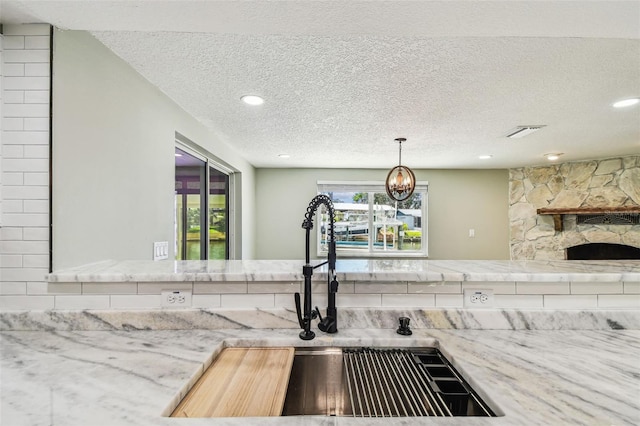 13909 Berkowitz Ave, Hudson, FL 34667 - kitchen view of a textured ceiling, recessed lighting, a fireplace, a chandelier, and light stone counters