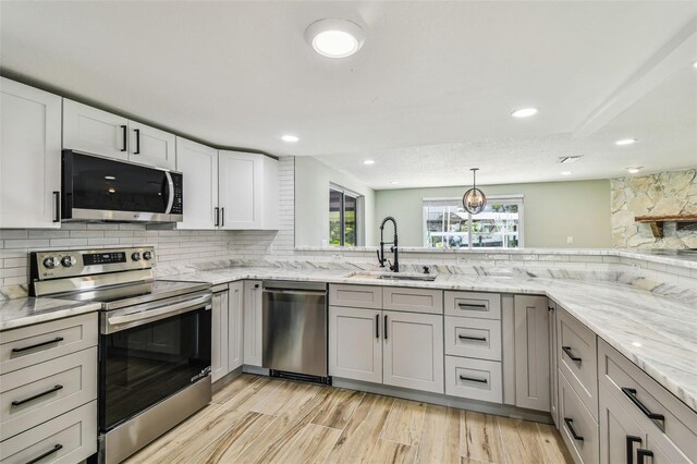 13909 Berkowitz Ave, Hudson, FL 34667 - kitchen featuring appliances with stainless steel finishes, decorative backsplash, light stone counters, recessed lighting, and light wood finished floors
