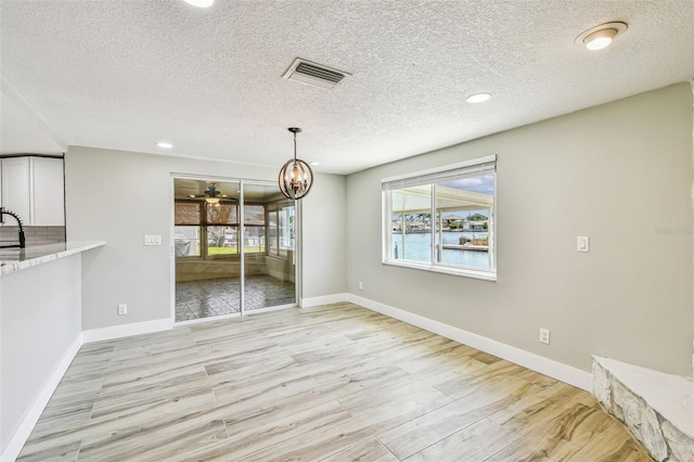 13909 Berkowitz Ave, Hudson, FL 34667 - unfurnished dining area with light wood-type flooring, a textured ceiling, a chandelier, a ceiling fan, and recessed lighting