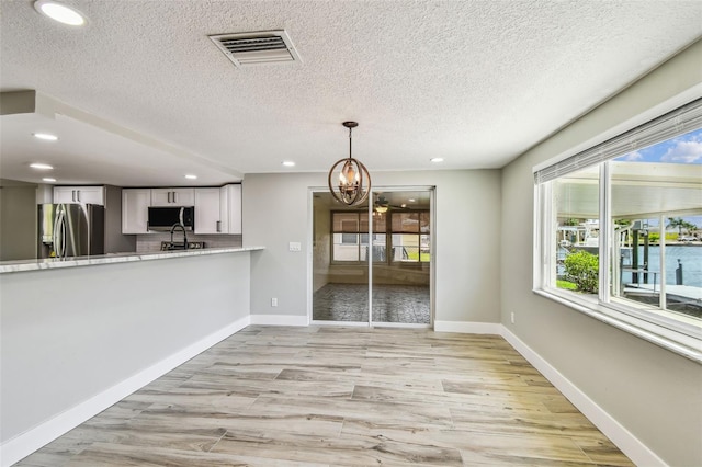 13909 Berkowitz Ave, Hudson, FL 34667 - unfurnished dining area with light wood finished floors, a chandelier, recessed lighting, healthy amount of natural light, and a textured ceiling