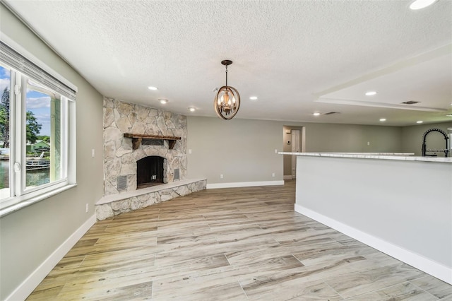 13909 Berkowitz Ave, Hudson, FL 34667 - unfurnished living room featuring a textured ceiling, recessed lighting, a fireplace, light wood-style flooring, and a chandelier