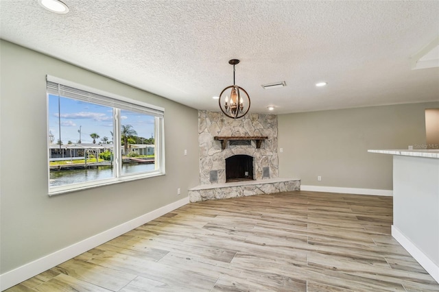 13909 Berkowitz Ave, Hudson, FL 34667 - unfurnished living room with a chandelier, a stone fireplace, wood finished floors, recessed lighting, and a textured ceiling