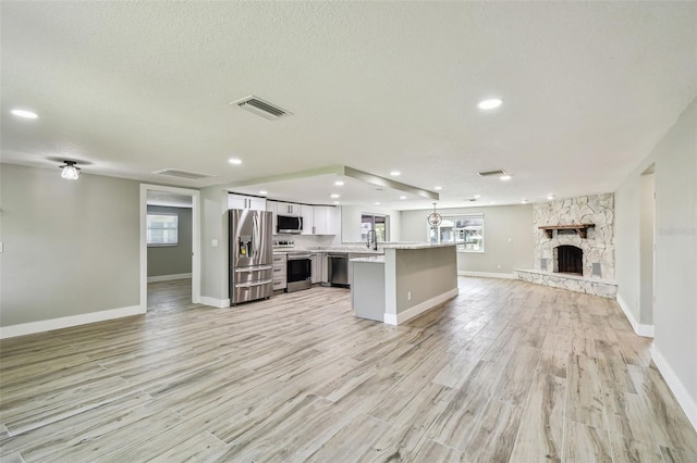 13909 Berkowitz Ave, Hudson, FL 34667 - unfurnished living room with light wood-style floors, a fireplace, a textured ceiling, and recessed lighting