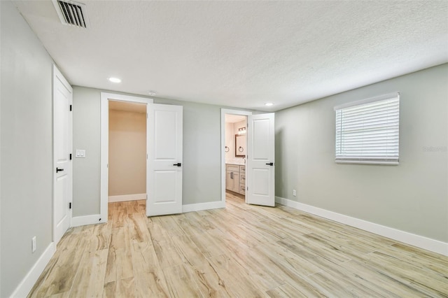 13909 Berkowitz Ave, Hudson, FL 34667 - unfurnished bedroom featuring light wood-style floors, recessed lighting, a textured ceiling, and connected bathroom