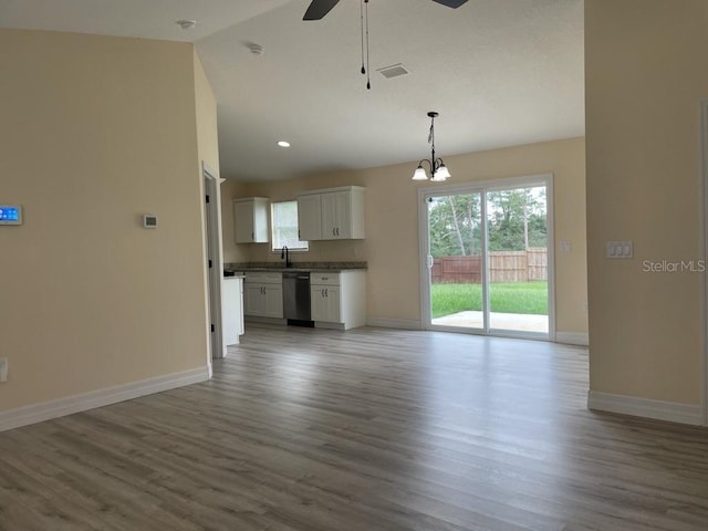 16910 SW 27th Ave, Ocala, FL 34473 - unfurnished living room featuring ceiling fan, vaulted ceiling, wood finished floors, healthy amount of natural light, and a chandelier