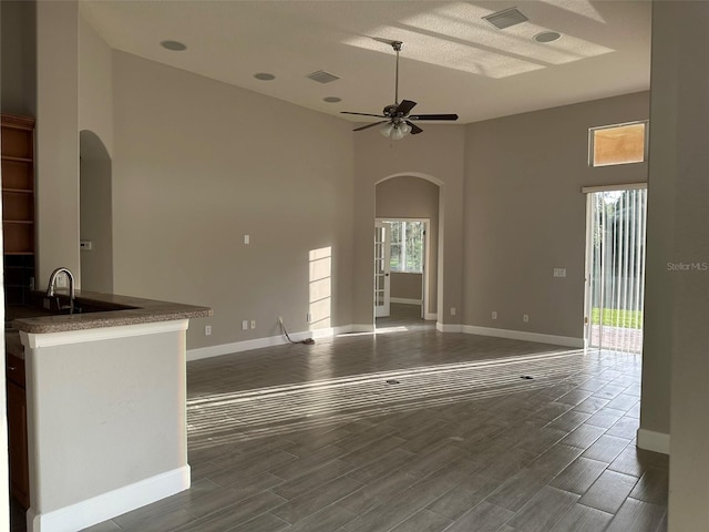1008 Arista Blvd, Valrico, FL 33594 - unfurnished living room featuring arched walkways, a high ceiling, dark wood finished floors, and a ceiling fan