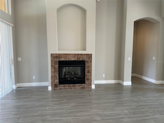 1008 Arista Blvd, Valrico, FL 33594 - unfurnished living room with wood tiled floors, arched walkways, a tile fireplace, and a towering ceiling