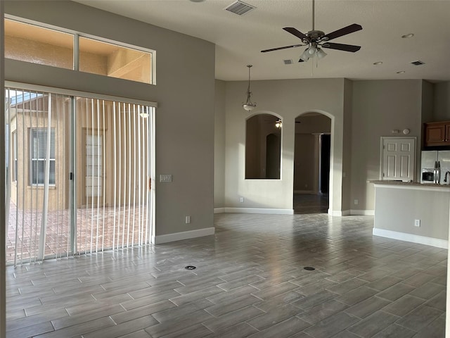 1008 Arista Blvd, Valrico, FL 33594 - unfurnished living room featuring arched walkways, wood tiled floors, ceiling fan, and a towering ceiling