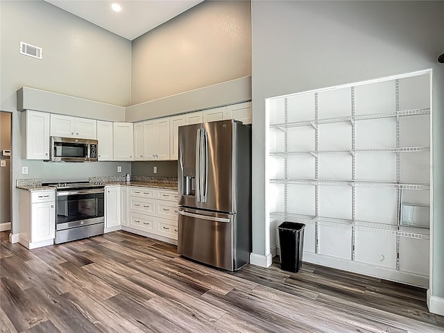 10206 Evening Trail Dr, Riverview, FL 33569 - kitchen featuring stainless steel appliances, a high ceiling, dark wood finished floors, white cabinetry, and light stone counters