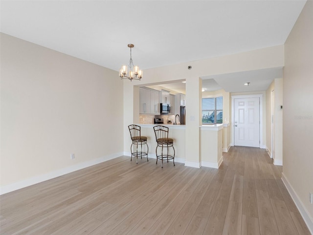 7979 Sailboat Key Blvd S Unit 505, South Pasadena, FL 33707 - kitchen featuring light wood-type flooring, a chandelier, light countertops, a breakfast bar, and stainless steel microwave