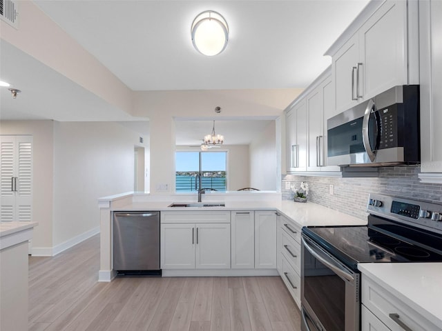 7979 Sailboat Key Blvd S Unit 505, South Pasadena, FL 33707 - kitchen with stainless steel appliances, backsplash, a chandelier, and light wood-style floors