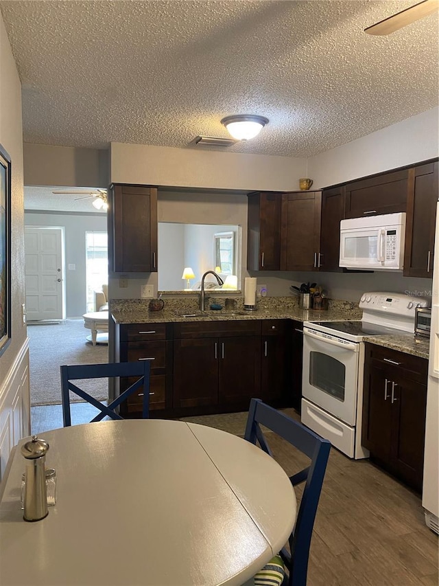 832 Cambridge Ct, Dunedin, FL 34698 - kitchen featuring white appliances, a ceiling fan, a textured ceiling, dark brown cabinetry, and wood finished floors