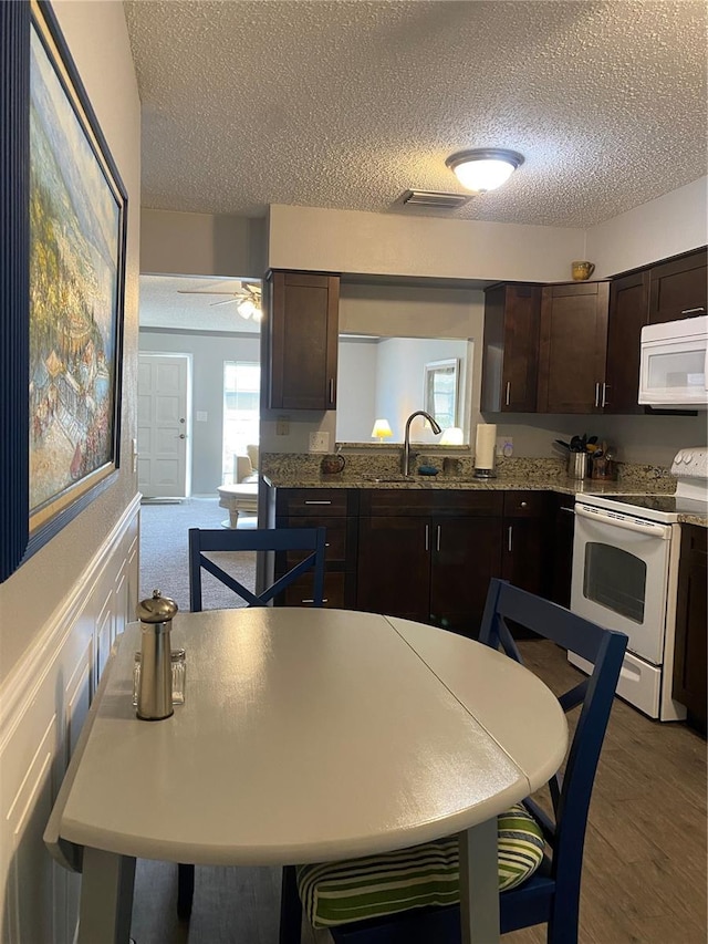 832 Cambridge Ct, Dunedin, FL 34698 - kitchen with white appliances, a textured ceiling, dark brown cabinets, a ceiling fan, and wood finished floors