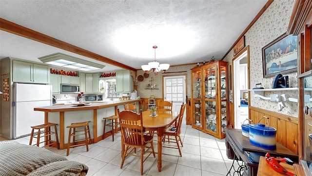 1753 Ranchette Rd, Wesley Chapel, FL 33543 - dining area featuring wallpapered walls, wainscoting, a chandelier, light tile patterned floors, and ornamental molding