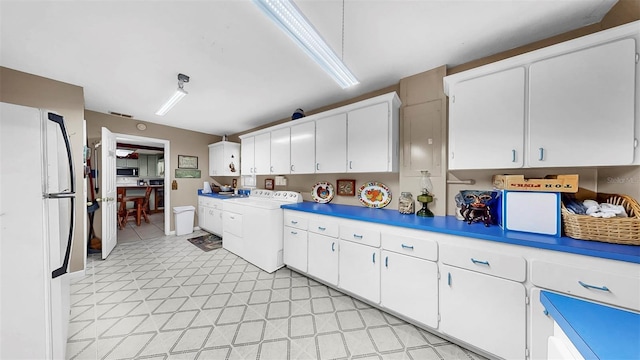 1753 Ranchette Rd, Wesley Chapel, FL 33543 - kitchen with freestanding refrigerator, washer and dryer, white cabinetry, light countertops, and stainless steel microwave