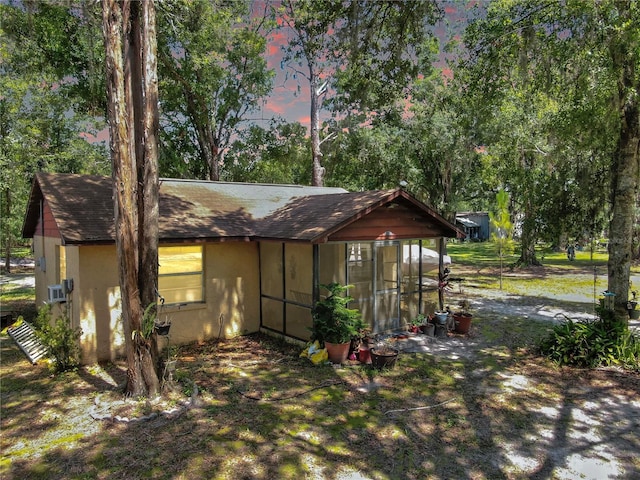 1753 Ranchette Rd, Wesley Chapel, FL 33543 - view of home's exterior with a sunroom, stucco siding, and roof with shingles