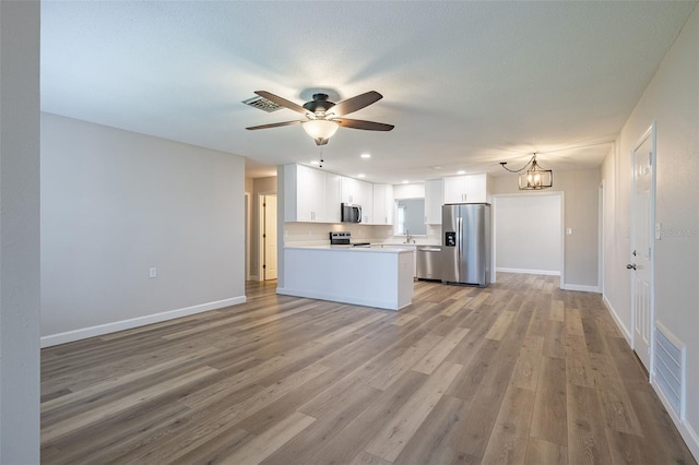 314 Circle Dr, Palm Harbor, FL 34683 - kitchen featuring appliances with stainless steel finishes, ceiling fan, white cabinetry, light wood-style flooring, and light countertops