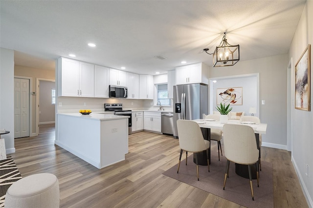 314 Circle Dr, Palm Harbor, FL 34683 - kitchen featuring appliances with stainless steel finishes, a chandelier, white cabinetry, light wood-type flooring, and recessed lighting