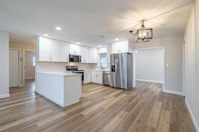 314 Circle Dr, Palm Harbor, FL 34683 - kitchen with stainless steel appliances, white cabinets, a chandelier, light countertops, and light wood finished floors