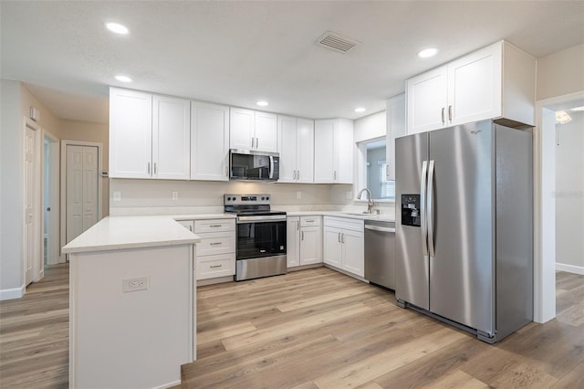 314 Circle Dr, Palm Harbor, FL 34683 - kitchen featuring appliances with stainless steel finishes, white cabinetry, light wood-type flooring, light countertops, and recessed lighting
