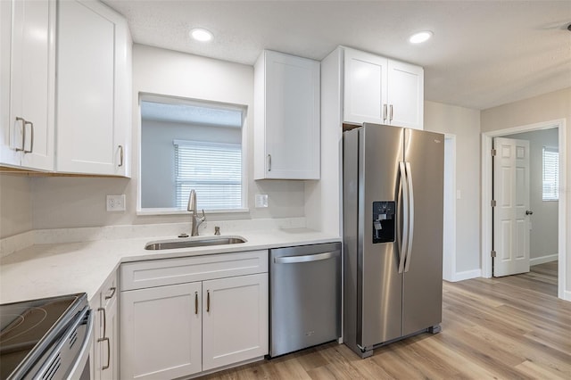 314 Circle Dr, Palm Harbor, FL 34683 - kitchen with stainless steel appliances, white cabinetry, light wood-style floors, recessed lighting, and a textured ceiling