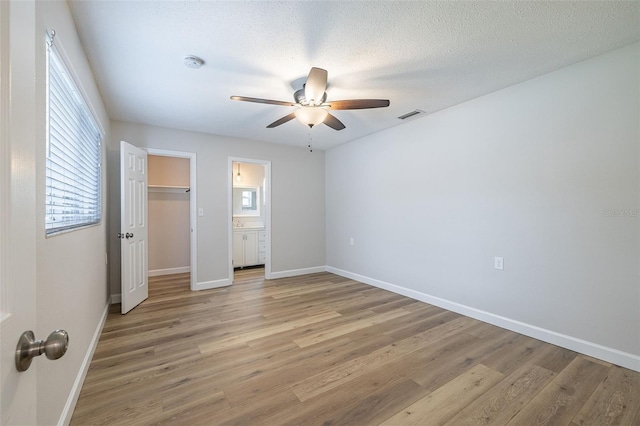 314 Circle Dr, Palm Harbor, FL 34683 - unfurnished bedroom with light wood-type flooring, a ceiling fan, a closet, and connected bathroom