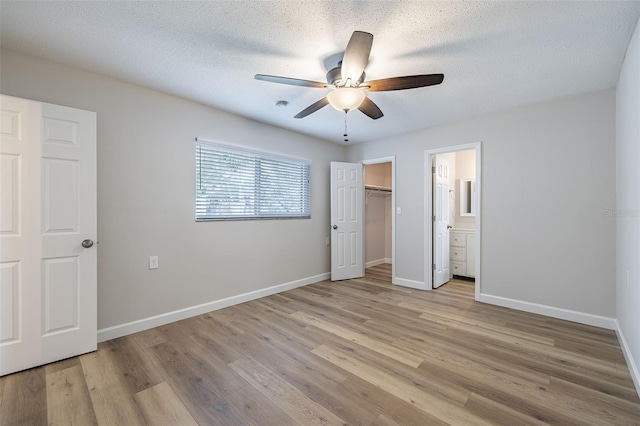 314 Circle Dr, Palm Harbor, FL 34683 - unfurnished bedroom featuring light wood-type flooring, a ceiling fan, connected bathroom, a closet, and a walk in closet