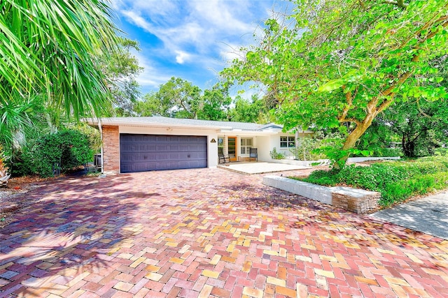 1578 Druid Rd S, Belleair, FL 33756 - view of front of house with a garage, decorative driveway, and stucco siding