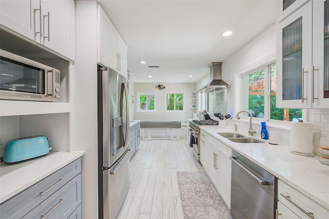 1578 Druid Rd S, Belleair, FL 33756 - kitchen with appliances with stainless steel finishes, wall chimney range hood, white cabinetry, light stone counters, and recessed lighting