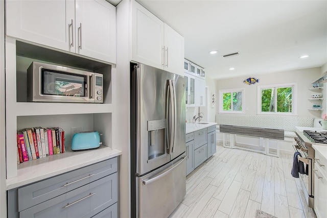 1578 Druid Rd S, Belleair, FL 33756 - kitchen featuring appliances with stainless steel finishes, gray cabinetry, white cabinetry, glass insert cabinets, and recessed lighting