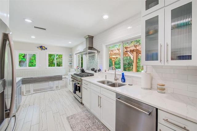 1578 Druid Rd S, Belleair, FL 33756 - kitchen featuring appliances with stainless steel finishes, island range hood, white cabinetry, backsplash, and light stone counters