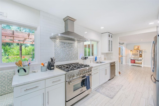 1578 Druid Rd S, Belleair, FL 33756 - kitchen featuring stainless steel appliances, exhaust hood, backsplash, white cabinetry, and light countertops