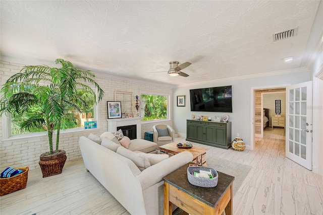 1578 Druid Rd S, Belleair, FL 33756 - living area featuring brick wall, ornamental molding, a ceiling fan, a glass covered fireplace, and light wood-type flooring