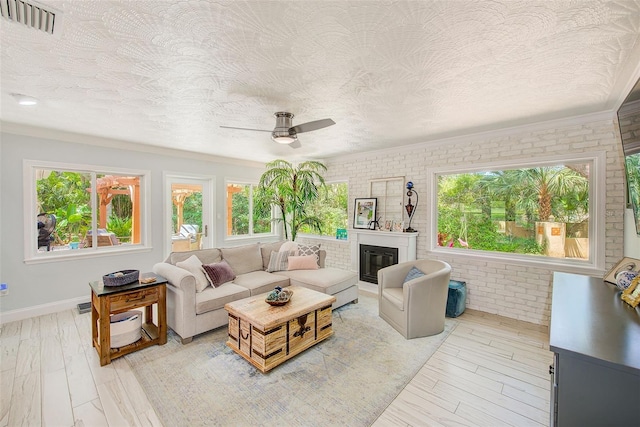 1578 Druid Rd S, Belleair, FL 33756 - living room with healthy amount of natural light, brick wall, a ceiling fan, a textured ceiling, and a glass covered fireplace