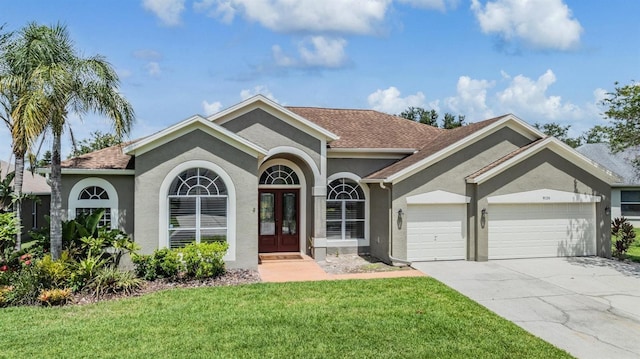 9126 Cypress Keep Ln, Odessa, FL 33556 - view of front facade with french doors, stucco siding, a garage, a front lawn, and concrete driveway
