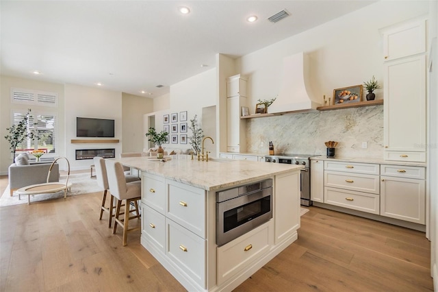 9126 Cypress Keep Ln, Odessa, FL 33556 - kitchen with stainless steel range with electric cooktop, custom range hood, open shelves, light wood-style floors, and recessed lighting