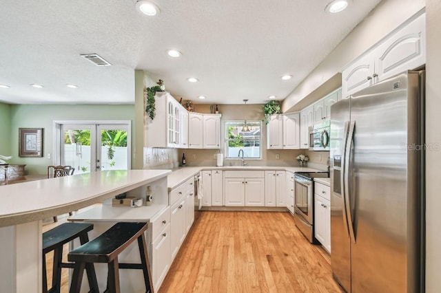 3304 W Harbor View Ave, Tampa, FL 33611 - kitchen featuring appliances with stainless steel finishes, a peninsula, a kitchen breakfast bar, white cabinetry, and french doors