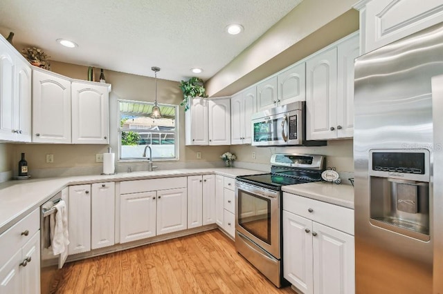3304 W Harbor View Ave, Tampa, FL 33611 - kitchen featuring stainless steel appliances, white cabinetry, pendant lighting, light wood-style flooring, and light countertops