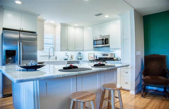 7941 58th Ave N Unit 301, Saint Petersburg, FL 33709 - kitchen featuring appliances with stainless steel finishes, light wood-style flooring, tasteful backsplash, white cabinets, and recessed lighting