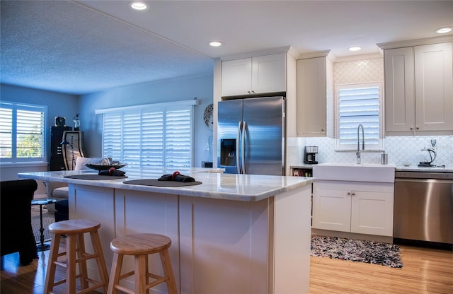 7941 58th Ave N Unit 301, Saint Petersburg, FL 33709 - kitchen featuring appliances with stainless steel finishes, light wood finished floors, a breakfast bar area, a kitchen island, and white cabinets