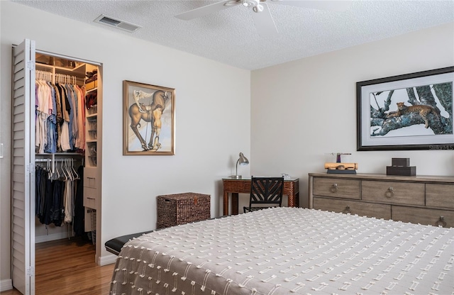 7941 58th Ave N Unit 301, Saint Petersburg, FL 33709 - bedroom with a walk in closet, a closet, wood finished floors, a textured ceiling, and ceiling fan