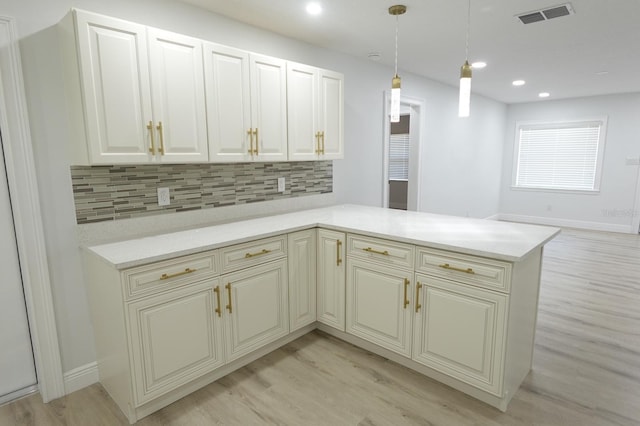 814 W 131st Ave, Tampa, FL 33612 - kitchen featuring light wood finished floors, decorative backsplash, pendant lighting, recessed lighting, and a peninsula