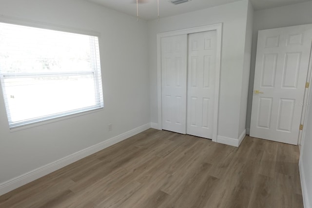 814 W 131st Ave, Tampa, FL 33612 - unfurnished bedroom with wood finished floors, multiple windows, and a closet